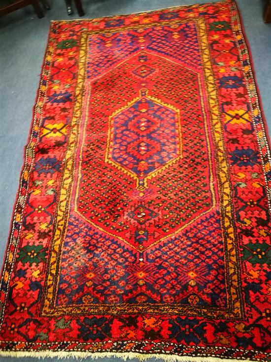An Eastern red ground rug, woven with a central elongated hexagon 215cm x 135cm